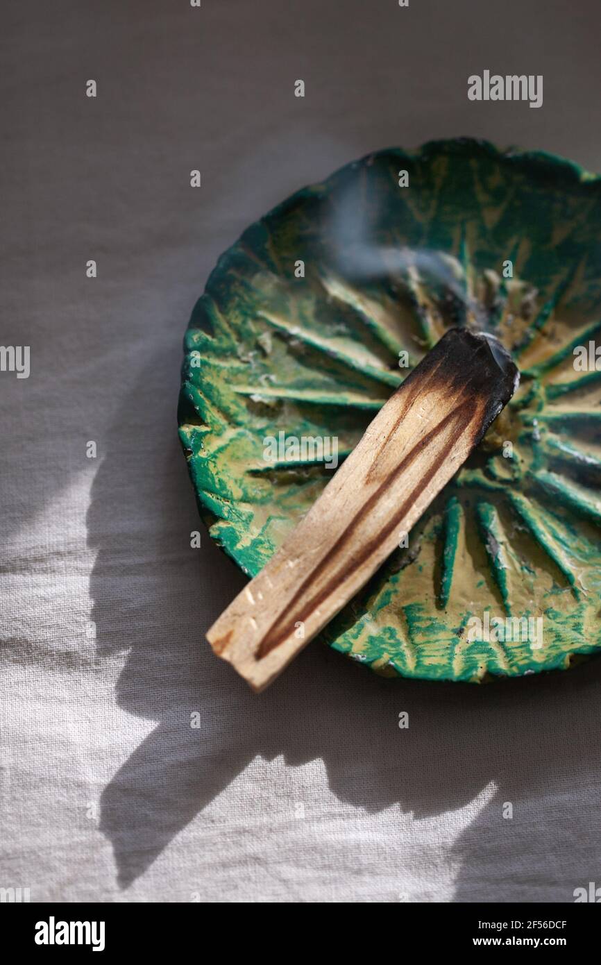 Bâton de palo santo brûlé sur plaque de céramique. Concept rituel antistress et relaxation Banque D'Images