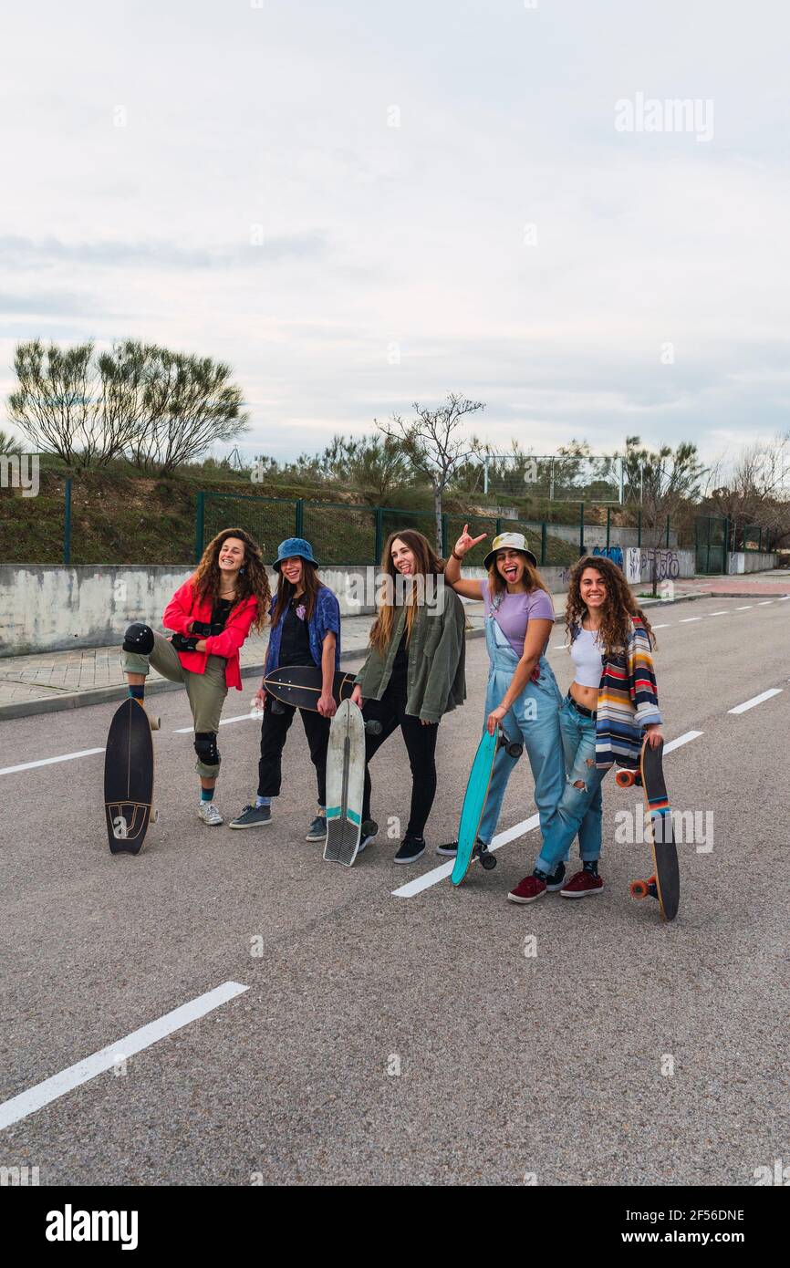 Des amies joyeuses avec des planches à roulettes sur la route Banque D'Images