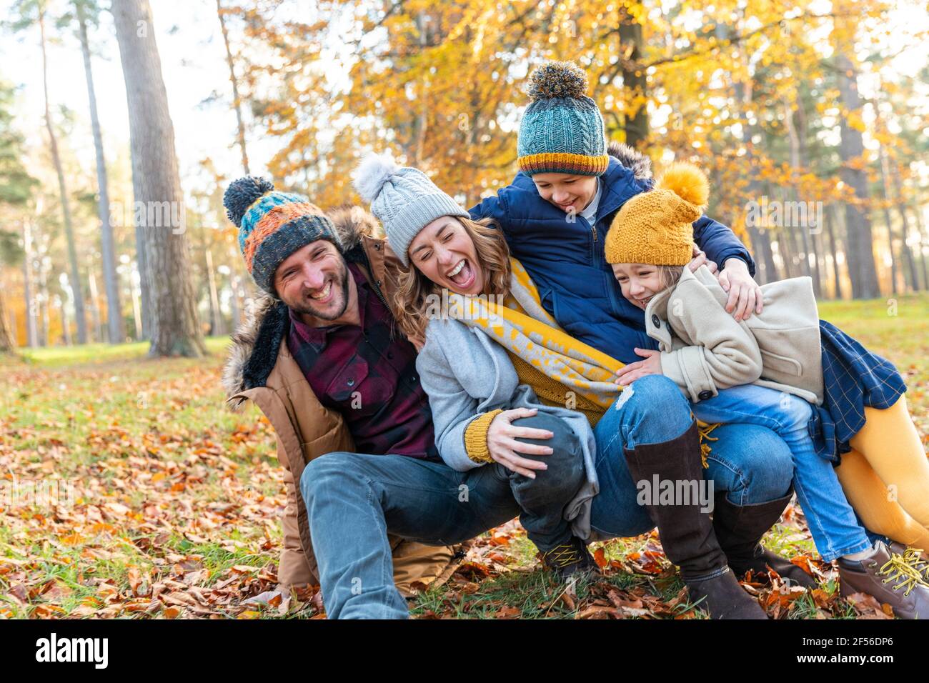 Famille ludique tombant les uns sur les autres tout en s'accroupiant dans la forêt Banque D'Images