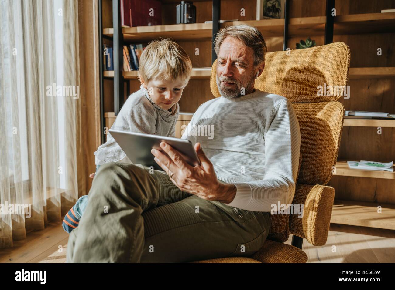 Un jeune garçon curieux qui regarde son père en utilisant une tablette numérique à la maison Banque D'Images