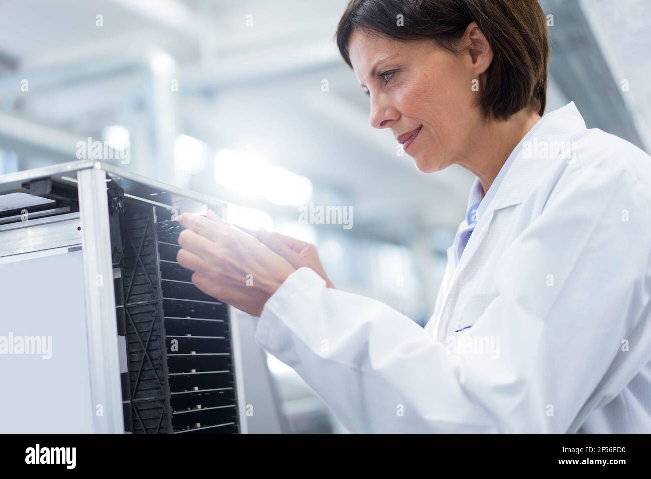 Une femme souriante qui analyse les machines de l'industrie Banque D'Images