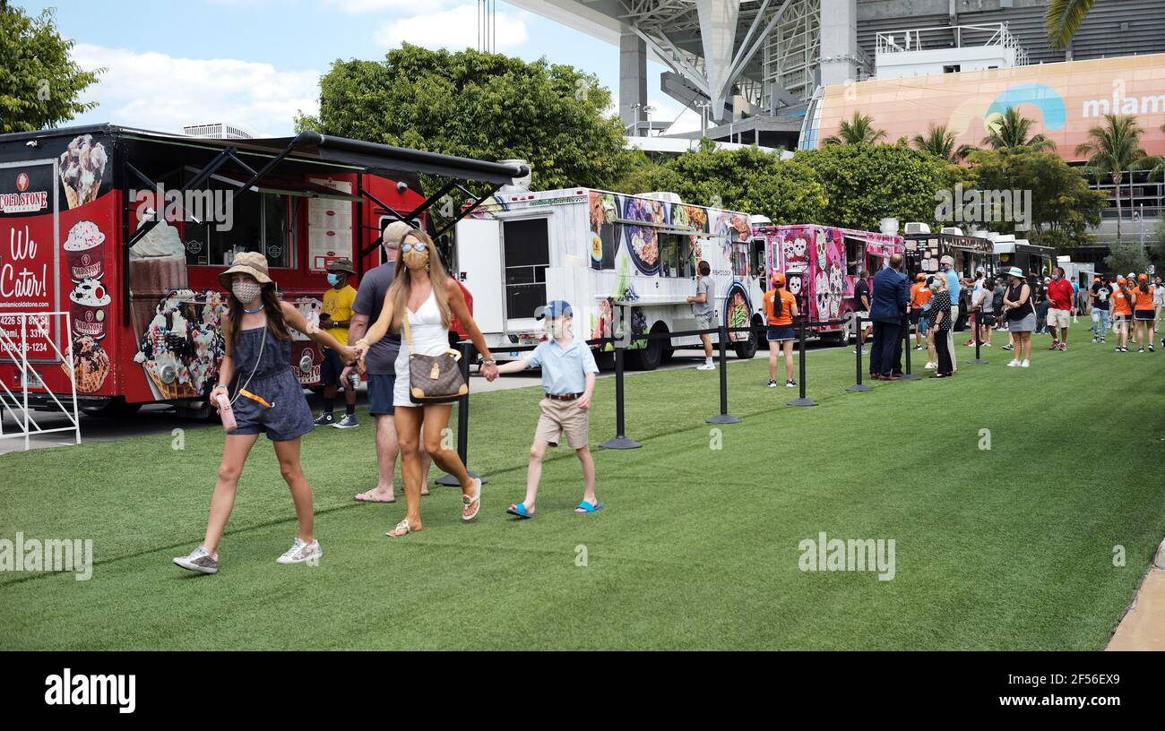 Miami Gardens, États-Unis. 24 mars 2021. Une famille de trois personnes portant leur masque passe devant les camions de nourriture qui sont alignés pour servir les joueurs, les médias et les quelques fans à l'Open de Miami au Hard Rock Stadium à Miami Gardens, en Floride, le mardi 23 mars 2021. Pour respecter les directives COVID-19, seulement environ 1000 participants seront autorisés chaque jour à regarder la pièce sur les différents tribunaux. Photo de Gary I Rothstein/UPI crédit: UPI/Alay Live News Banque D'Images