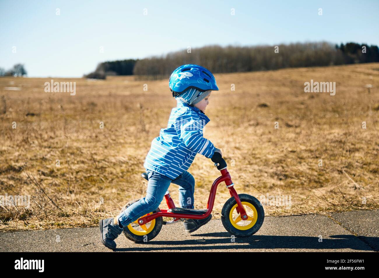 Garçon portant un casque de vélo, vélo d'équilibre sur la route Banque D'Images