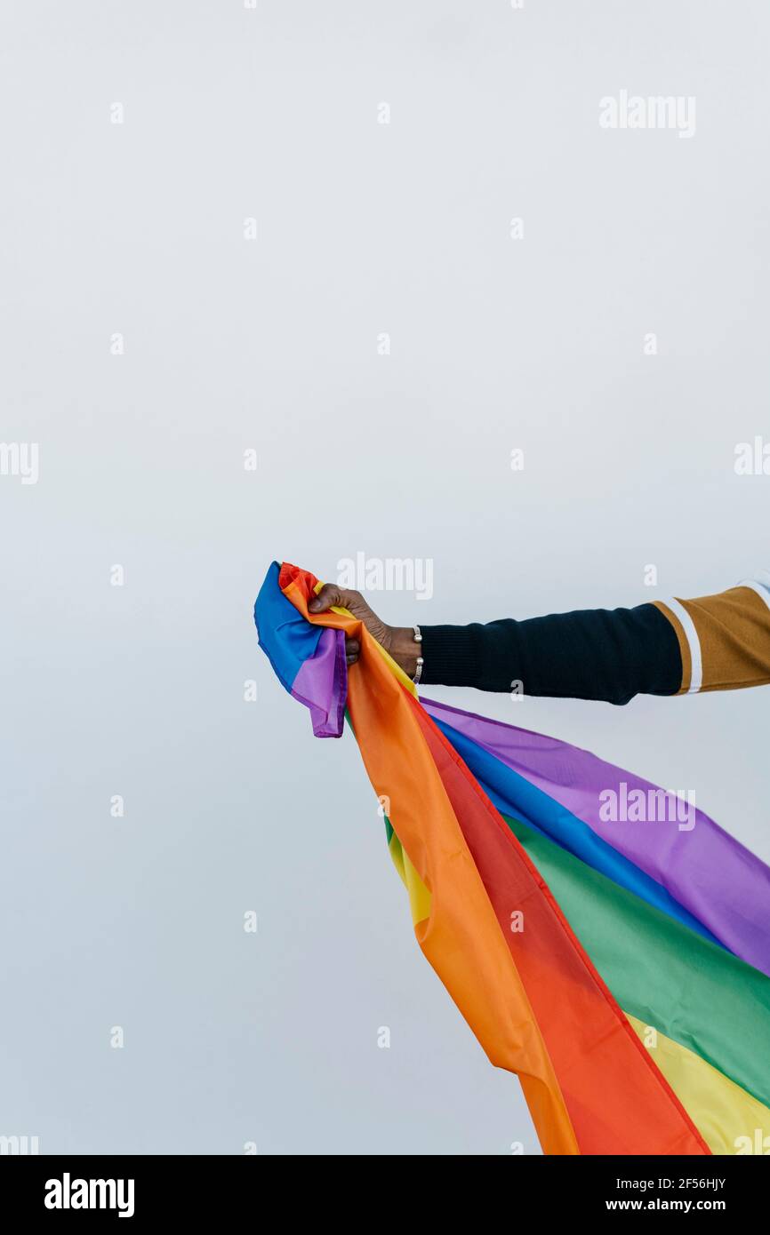 Homme africain portant le drapeau LGTBQI contre le mur blanc Banque D'Images