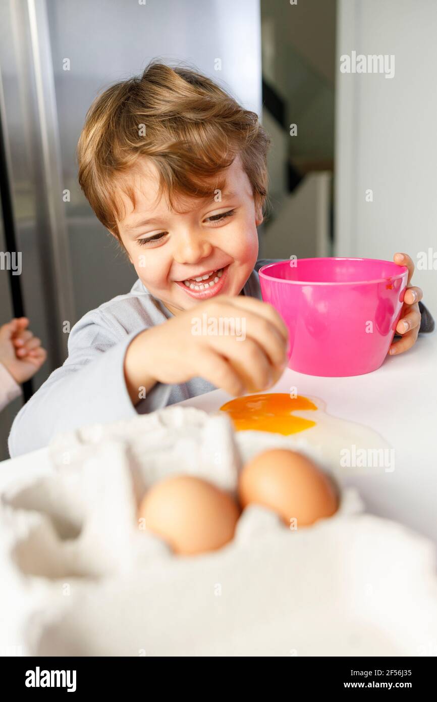 Adorable garçon regardant la sœur casser l'œuf dans le bol de la cuisine Banque D'Images