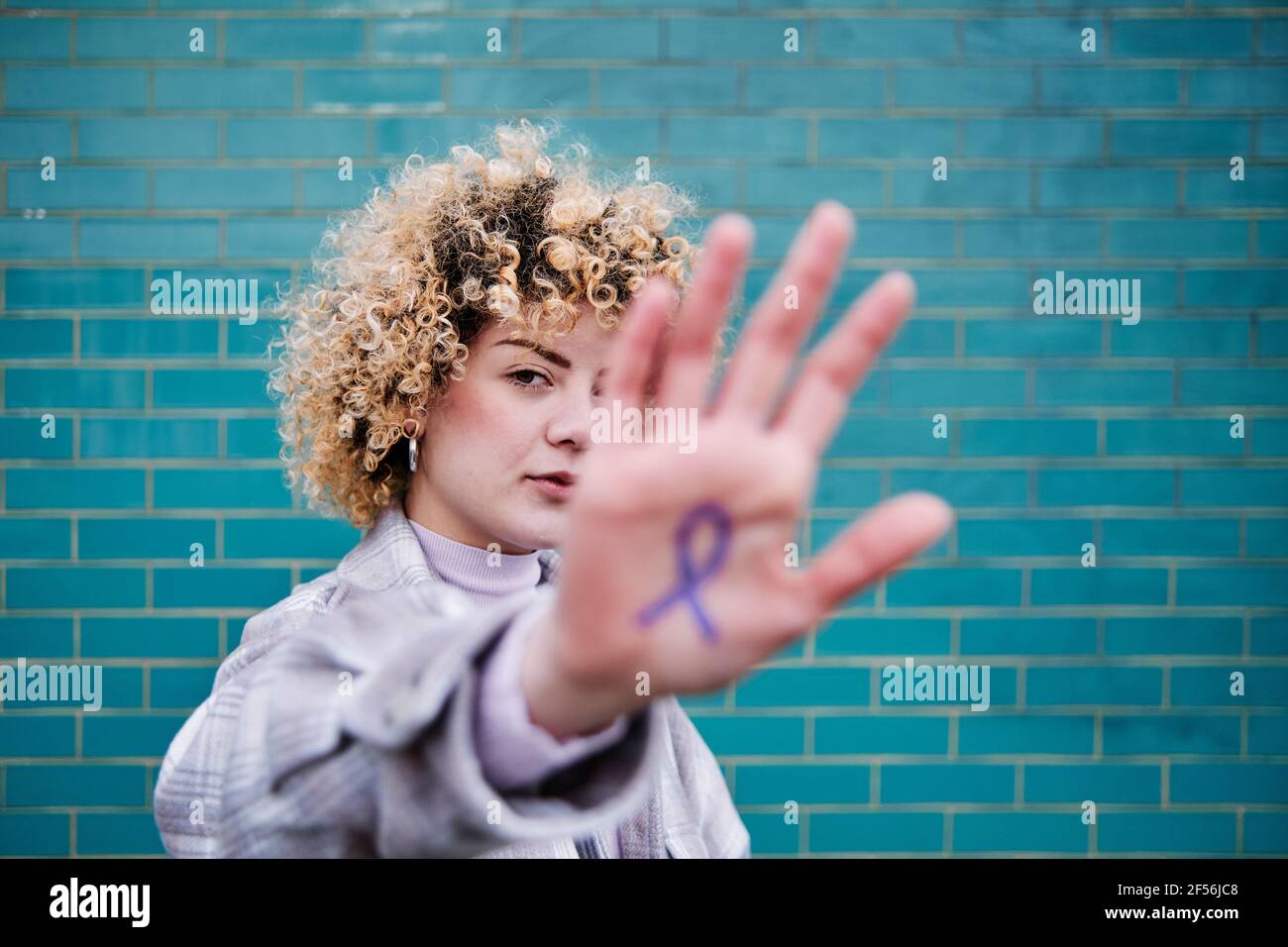 Femme aux cheveux bouclés montrant le symbole du ruban du cancer du côlon à portée de main Banque D'Images
