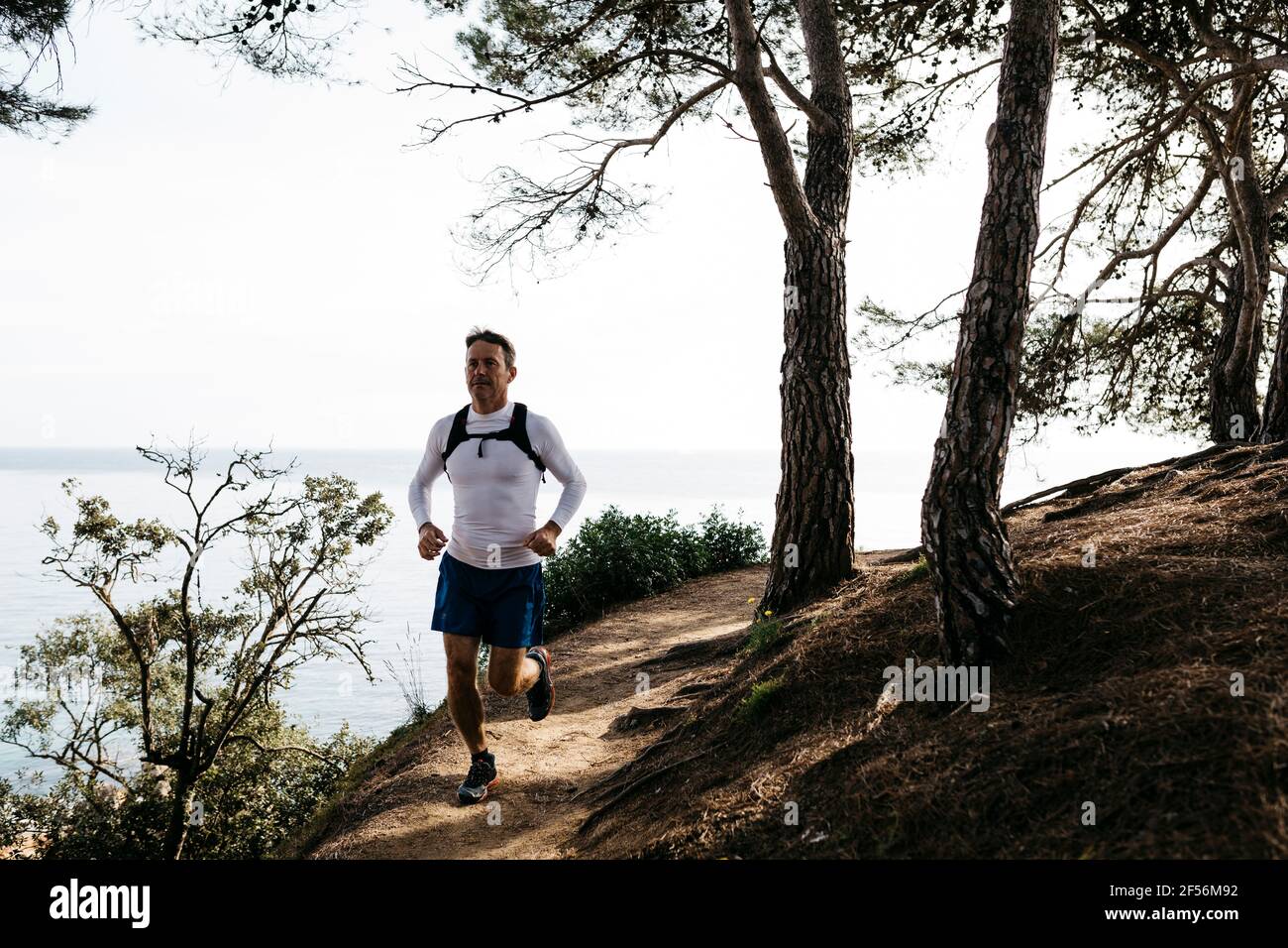 Homme en train de courir sur un sentier près de la forêt contre un ciel dégagé Banque D'Images