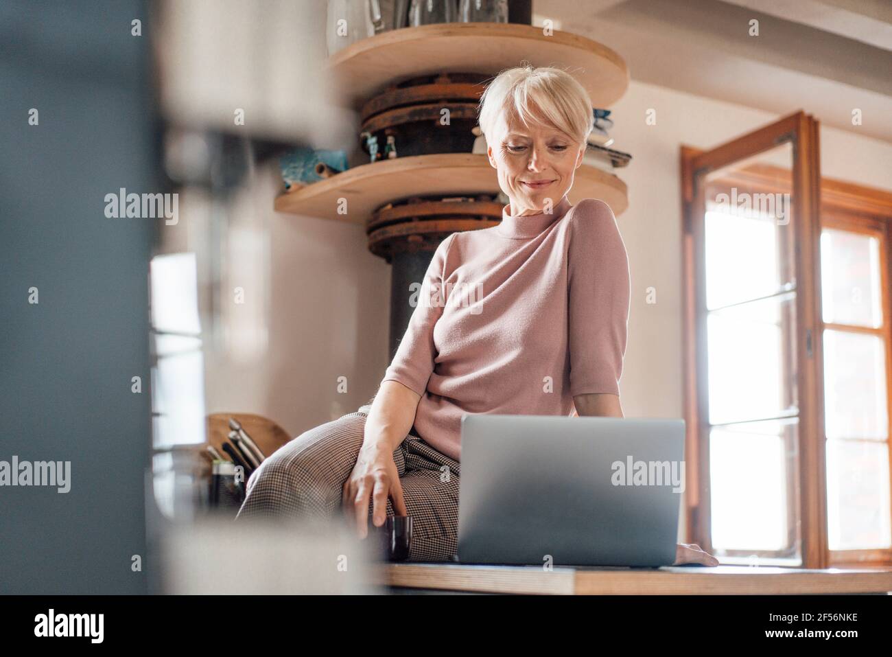 Femme indépendante avec ordinateur portable sur le comptoir de la cuisine à accueil Banque D'Images
