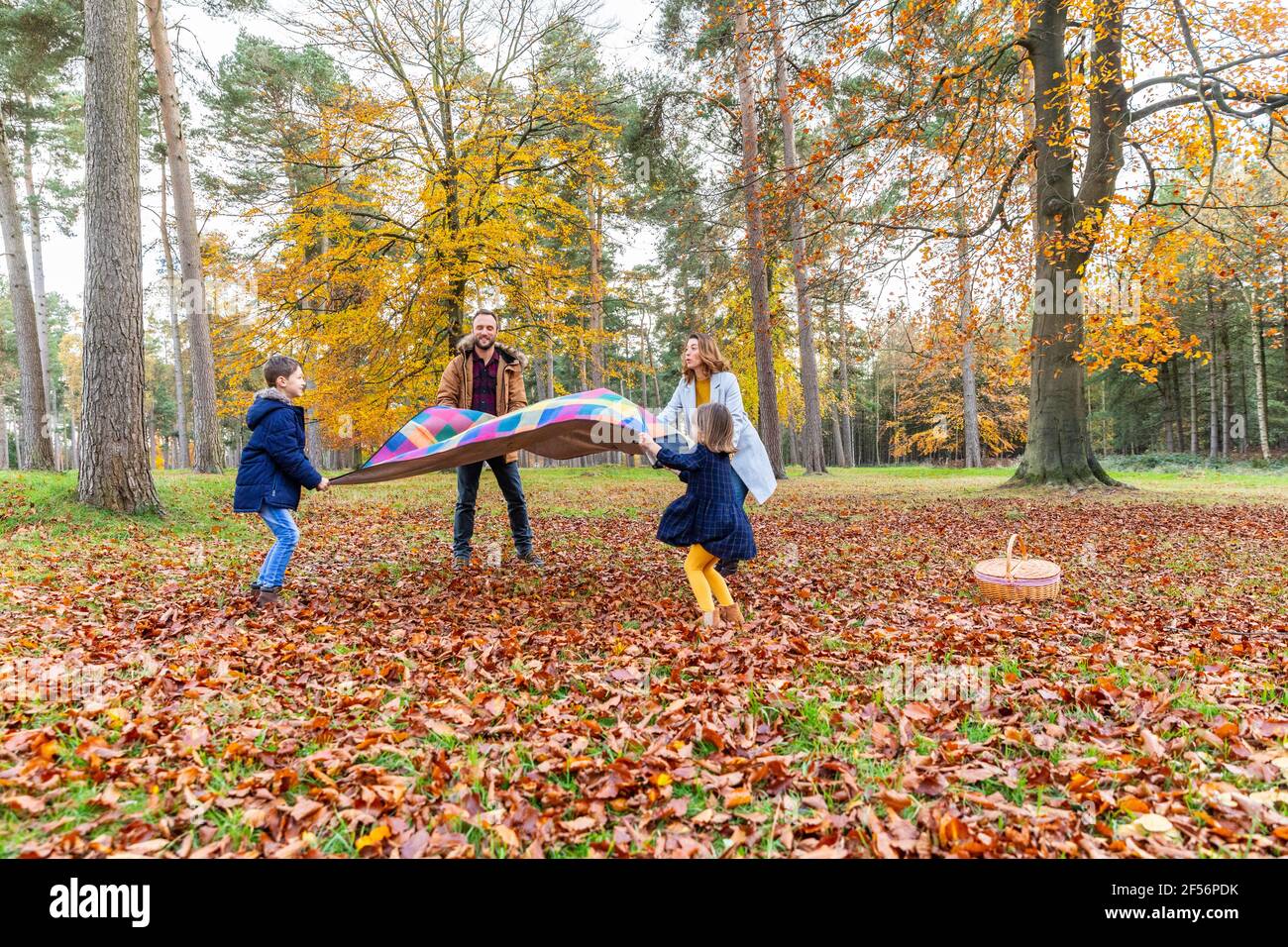 Famille tenant une couverture en se tenant dans la forêt pendant l'automne Banque D'Images