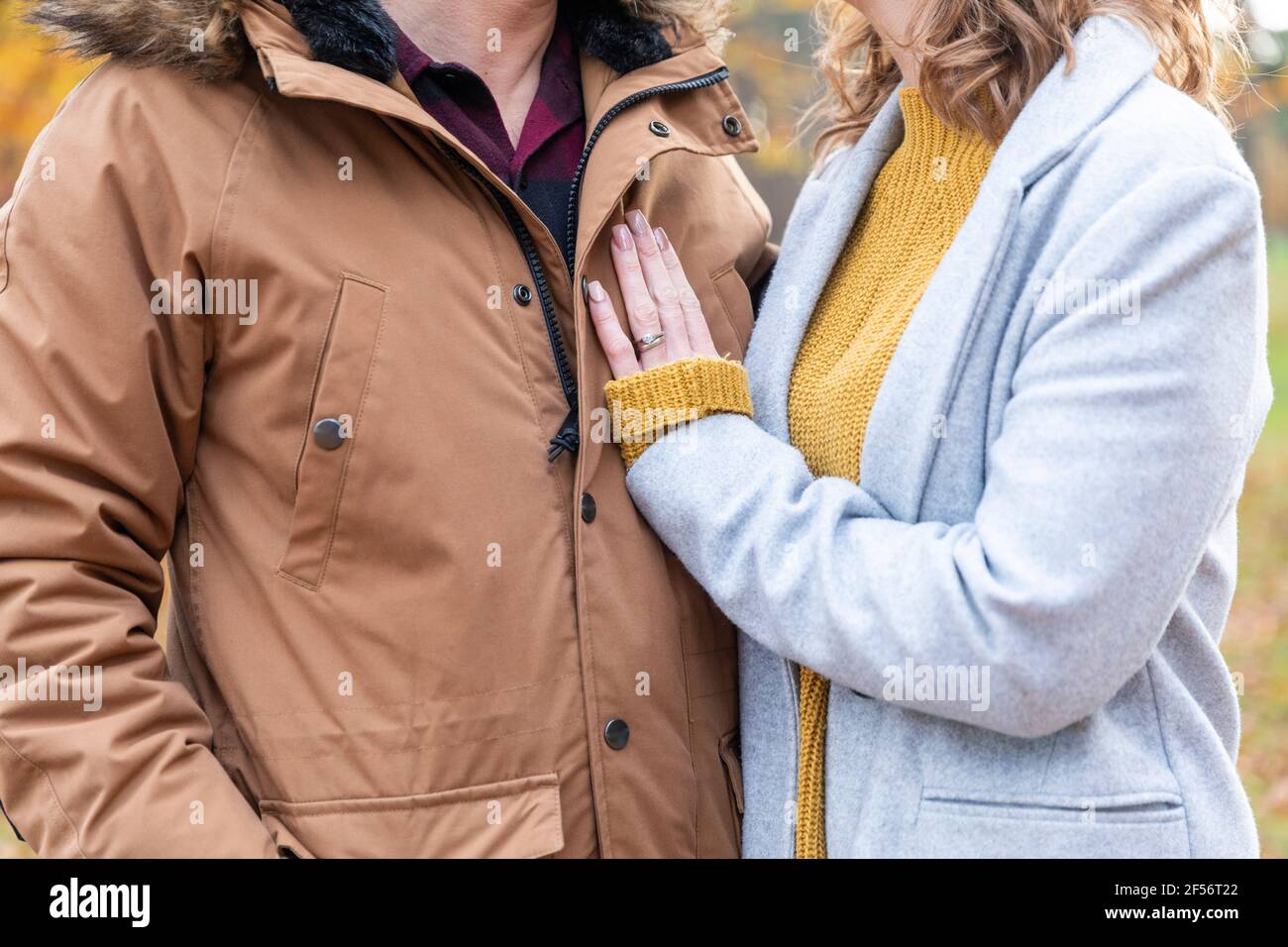 Couple portant une veste debout ensemble en forêt Banque D'Images
