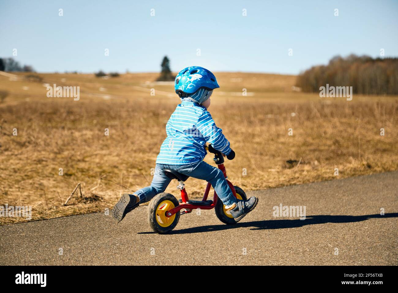 Garçon avec un casque de vélo balance vélo sur la route Banque D'Images