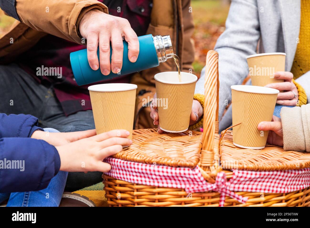Le père verse du café dans une tasse tout en étant assis avec sa famille forêt Banque D'Images