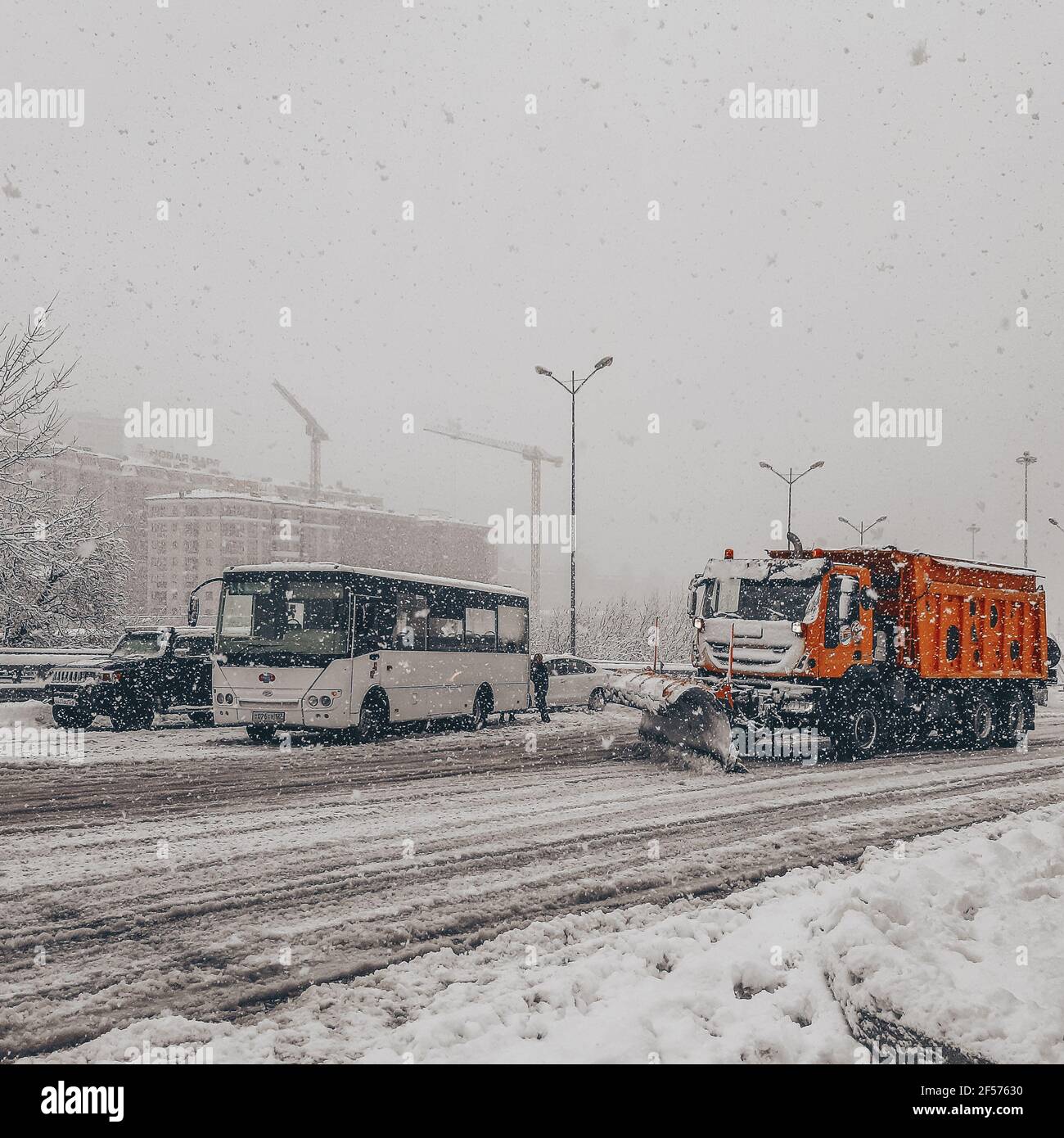 Les autobus et autres voitures remorqueraient sur une route enneigée pendant un blizzard pendant que le chasse-neige élimine la neige Banque D'Images