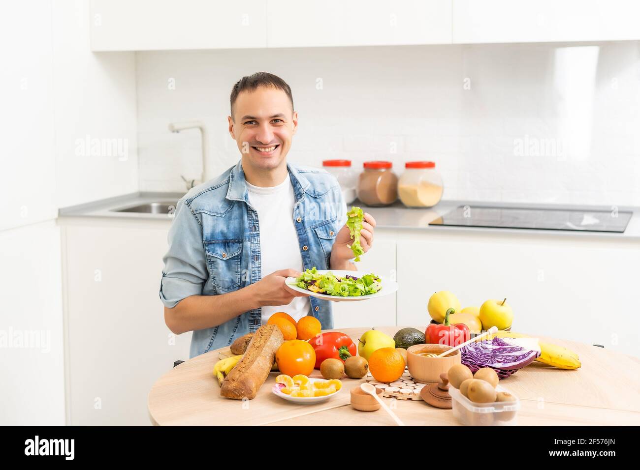 Joyeux jeune homme préparant un dîner romantique recherche de recettes de légumes Menu de régime, mari souriant cuisant la nourriture végétalienne saine salade coupée dans la cuisine Banque D'Images