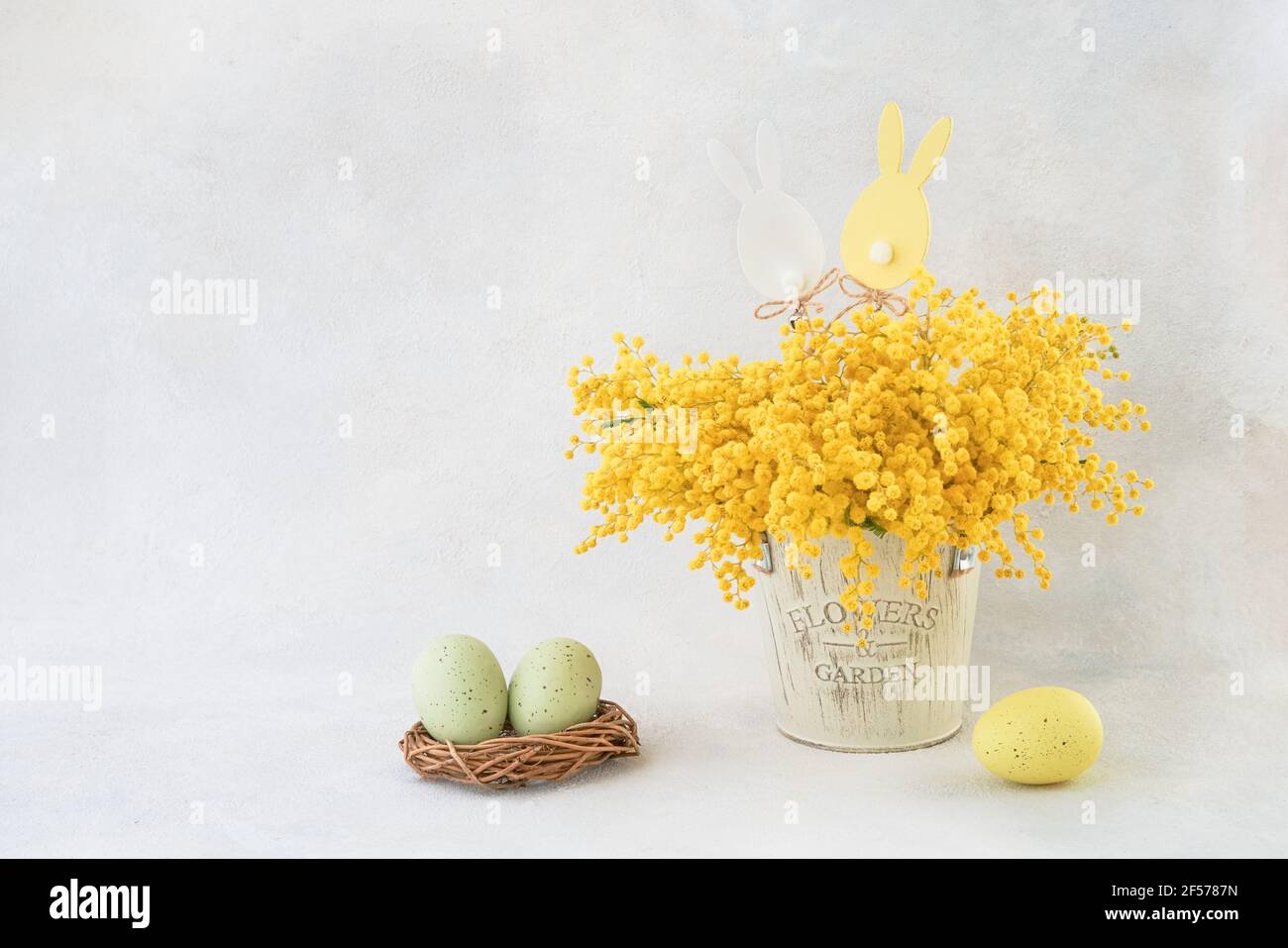 Décoration de Pâques et bouquet de fleurs Mimosa dans un vase sur fond clair. Copier l'espace pour le texte Banque D'Images