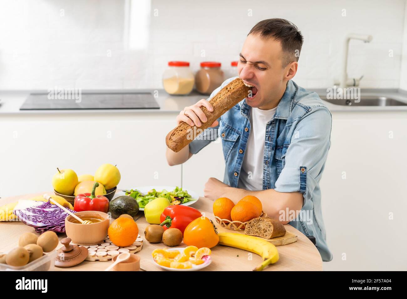 Joyeux jeune homme préparant un dîner romantique recherche de recettes de légumes Menu de régime, mari souriant cuisant la nourriture végétalienne saine salade coupée dans la cuisine Banque D'Images