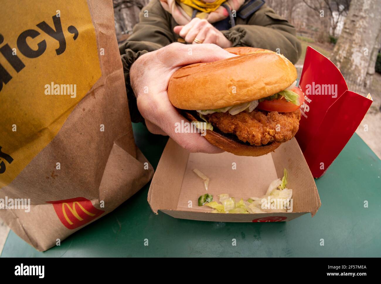 Un dîner se prépare à déjeuner dans un sandwich au poulet croustillant McDonald’s de luxe tout en dînant en plein air à New York le mercredi 17 mars 2021. En 2019, Popeye a lancé son sandwich au poulet avec un grand succès, ce qui a conduit à peu près toutes les chaînes alimentaires rapides à produire un menu de poulet croustillant. McDonald’s est enfin entré dans le rôle de gorille de 800 livres et a déjà conduit à une augmentation de la circulation à pied dans ses restaurants. (© Richard B. Levine) Banque D'Images