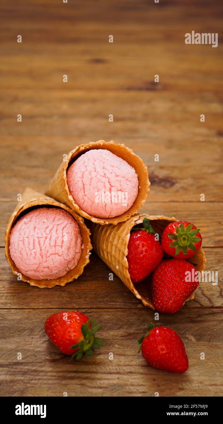 Glace à la fraise dans un cône à gaufres. Baies rouges et boules de crème glacée Banque D'Images