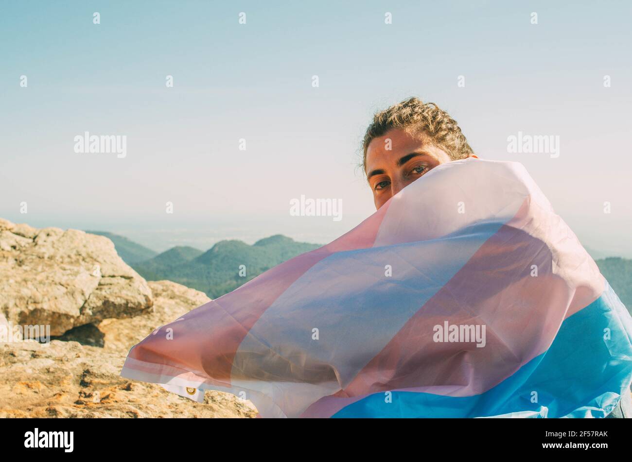 Jeune homme espagnol avec le drapeau trans sur ses épaules sur un sommet de montagne Banque D'Images