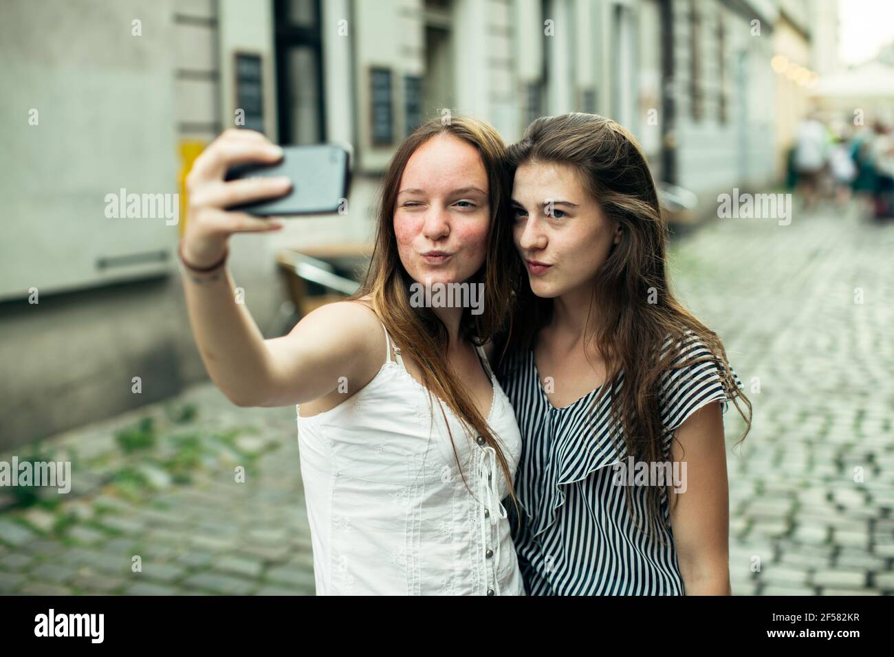 Deux petites filles prennent un selfie sur smartphone en plein air dans la vieille ville. Banque D'Images