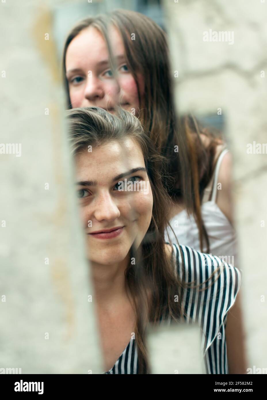 Le reflet de deux filles amis dans un éclat d'un miroir dans la rue. Banque D'Images