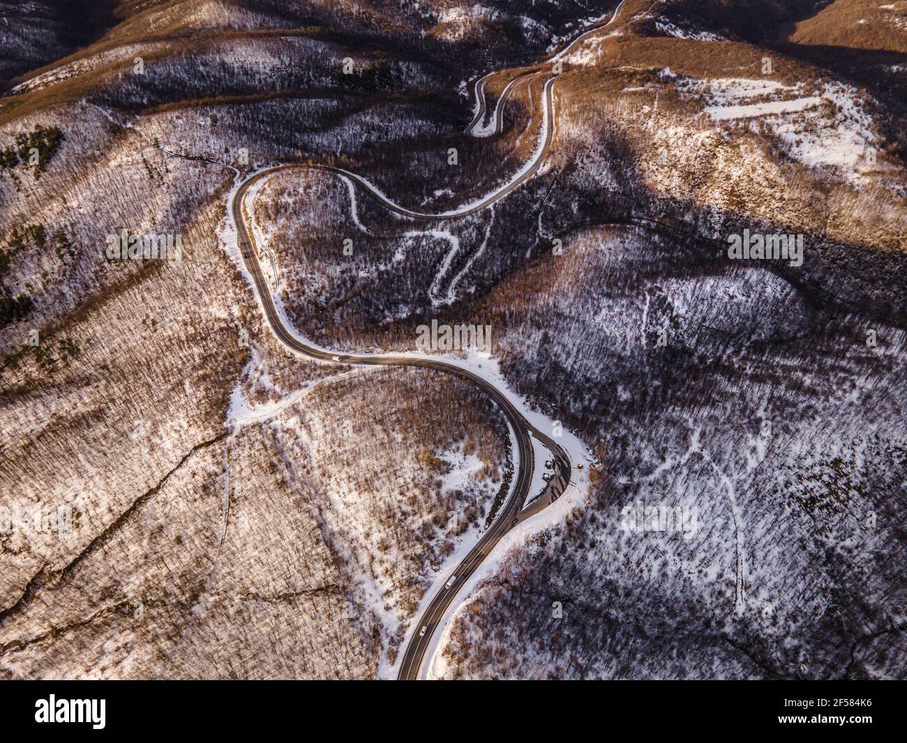 Image de drone de vue aérienne à grand angle sur la spirale incurvée route à travers les arbres et la forêt dans la chaîne de montagne avec Neige blanche en hiver près de Knja Banque D'Images
