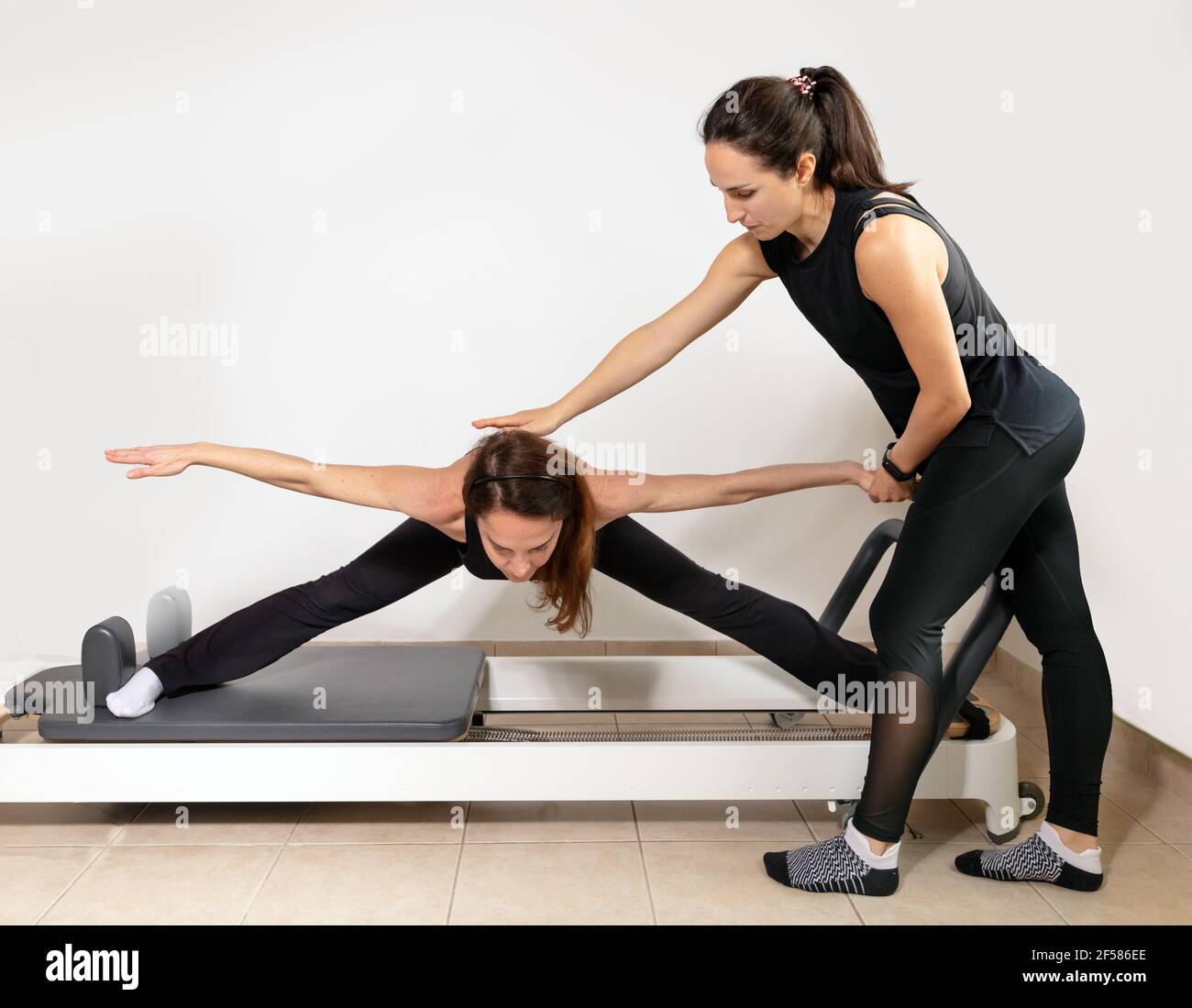 Une femme pratiquant des exercices avec un entraîneur personnel pilates. Banque D'Images