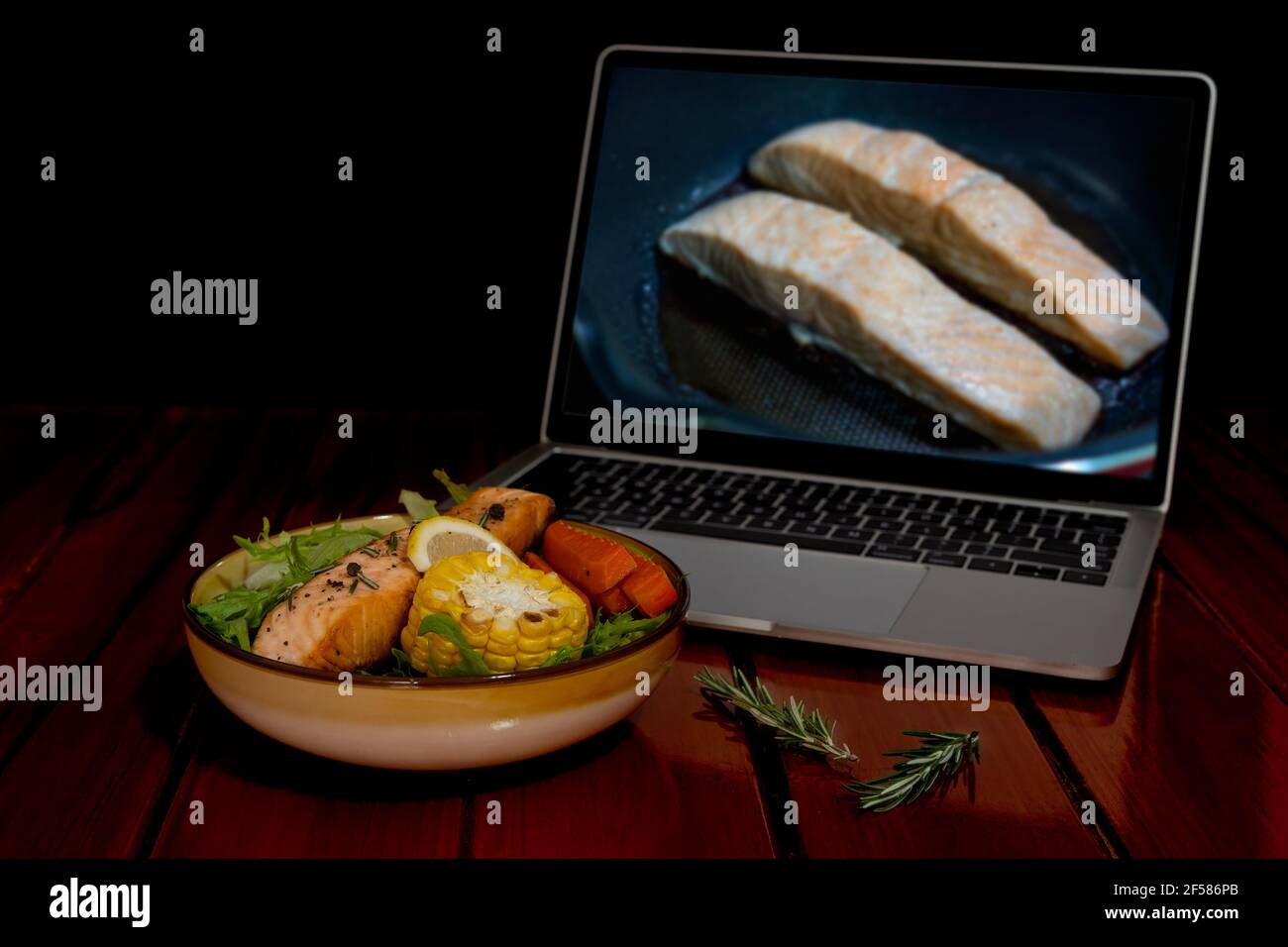 Salade de saumon grillé, laitue, maïs grillé, carotte, citron, Romarin. Trouvez des recettes de cuisine à partir d'un ordinateur portable via Internet. Banque D'Images