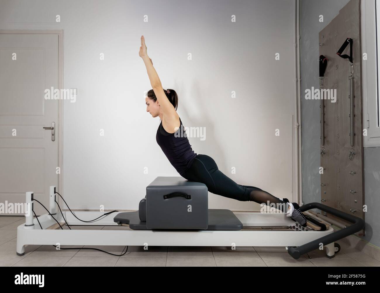 Une femme faisant des exercices de pilates sur un lit réformé. Banque D'Images
