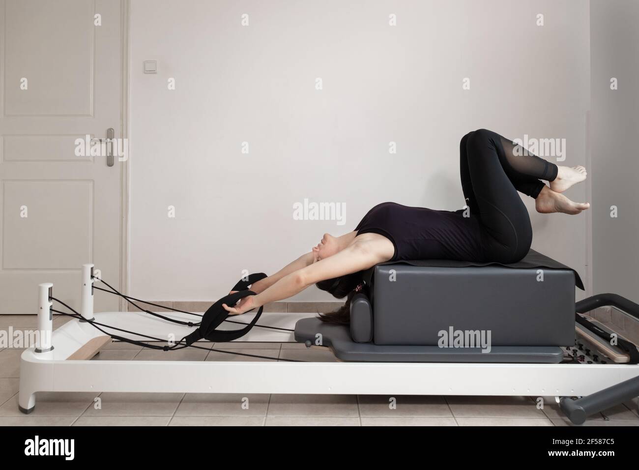 Une femme faisant des exercices de pilates sur un lit réformé. Banque D'Images