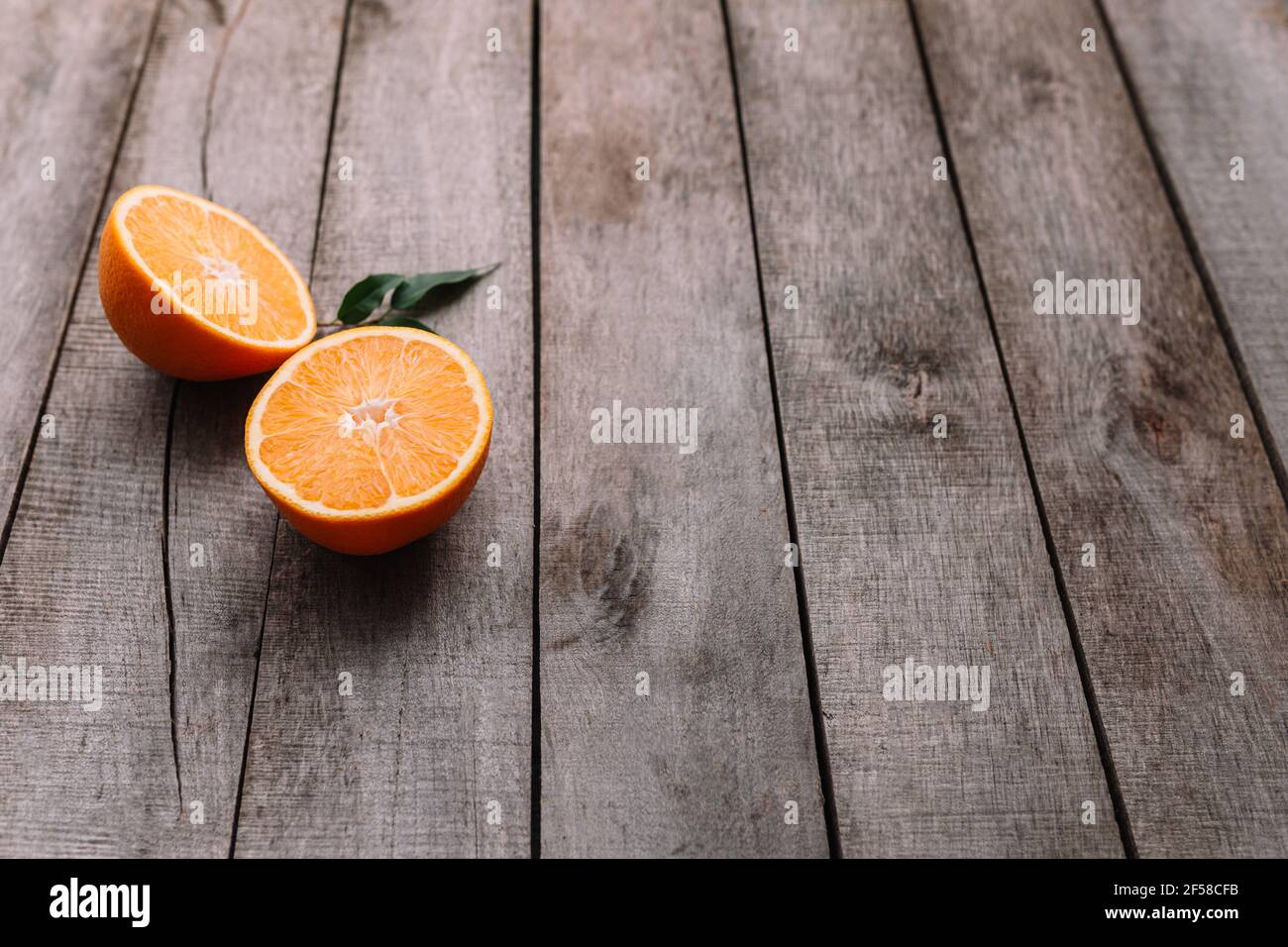 Plat avec des tranches de fruits d'orange mûres fraîches sur fond de bois gris. Pulpe d'orange et feuilles vertes. Concept de nourriture tropique. Alimentation saine co Banque D'Images