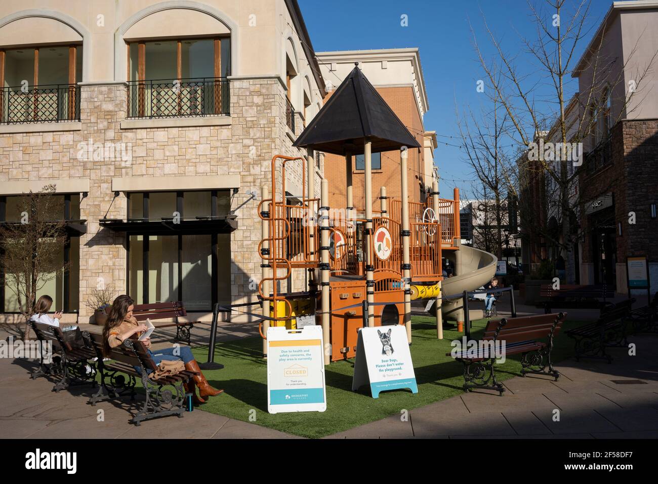 Les amateurs de shopping se reposent sur des bancs dans une aire de jeux fermée du centre commercial Bridgeport Village tout en pratiquant la distanciation sociale le mercredi 3 mars 2021. Banque D'Images