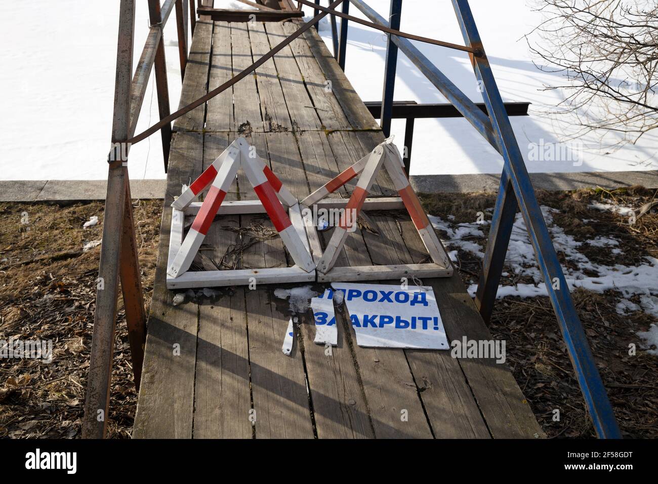 Interdiction de panneaux et d'une planche en russe « le passage est interdit » à l'entrée du pont en bois étroit Banque D'Images