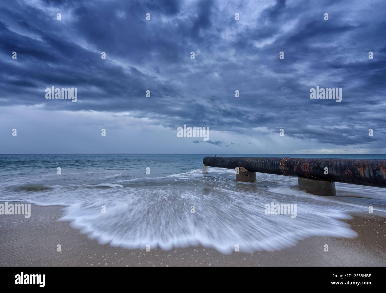 Drain de tempête déversant de l'eau dans l'océan à la plage de sable Banque D'Images