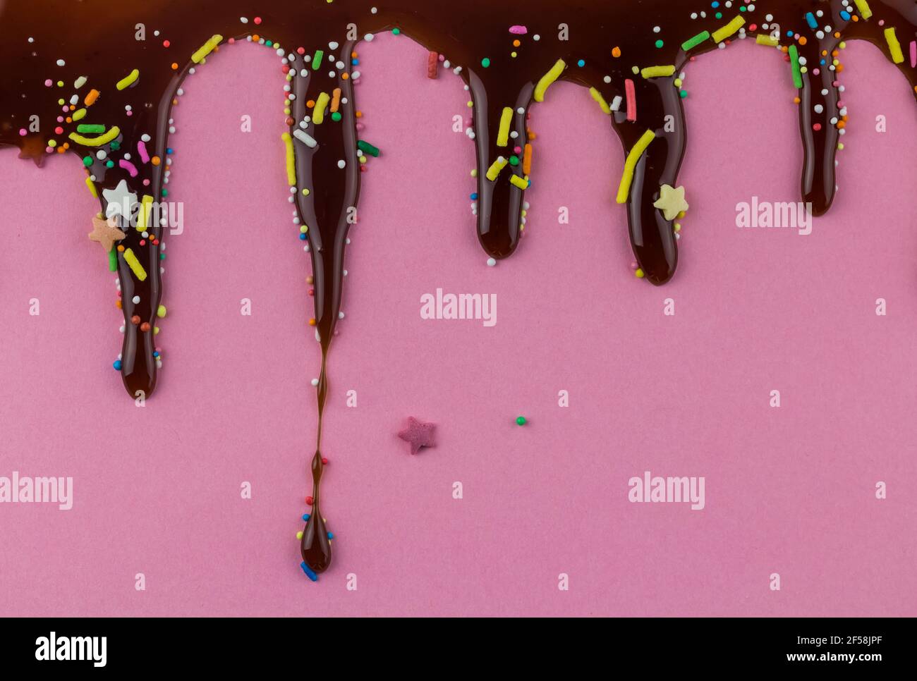 Goutte de chocolat sur fond rose avec des points, des saupoudres et des étoiles amusantes - espace pour copier la carte d'invitation d'anniversaire Banque D'Images
