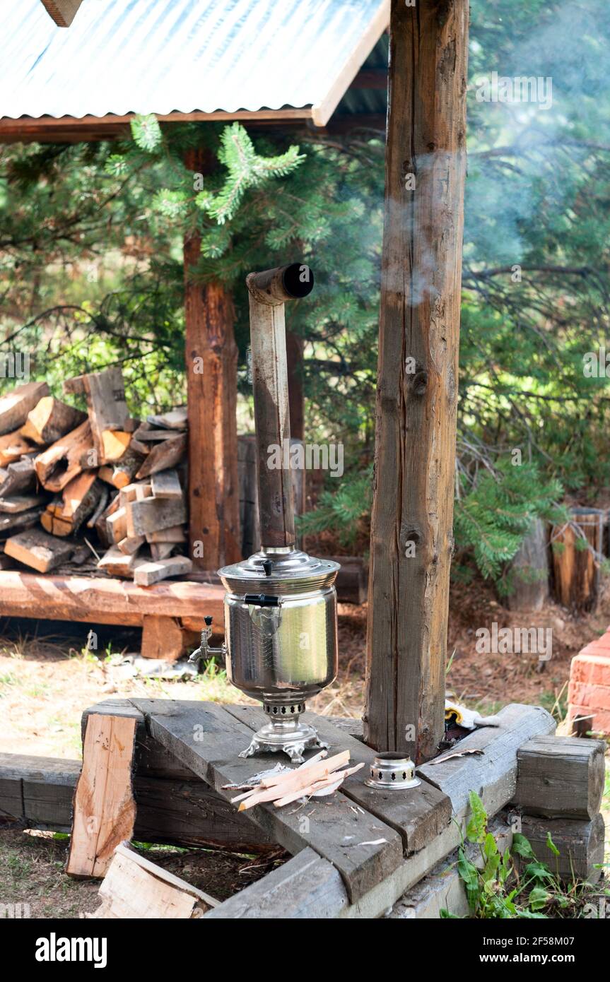 Fumant samovar russe, réservoir d'ébullition en métal avec tuyau comme cheminée pour brûler des bûches de feu, image verticale Banque D'Images