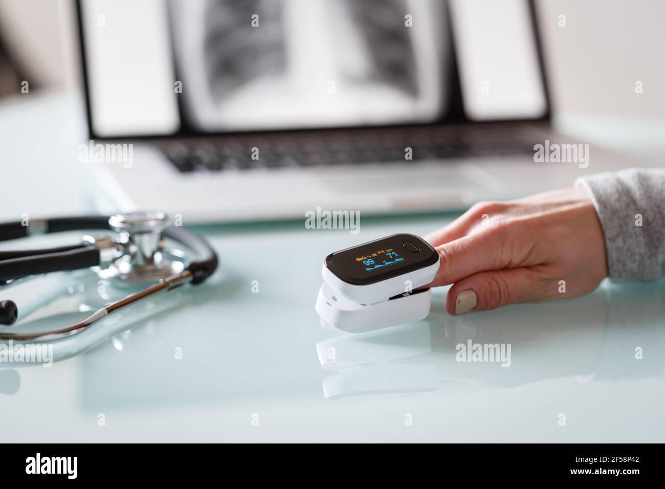 Patient de main féminine mesurant la saturation en oxygène et le pouls à l'aide d'un oxymètre portable. Concept de soins de santé Banque D'Images
