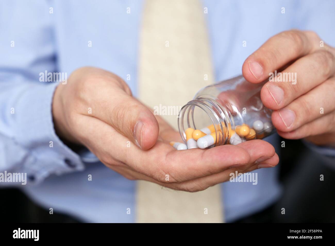 Homme dans les vêtements de bureau prenant des pilules, bouteille de médicament dans les capsules de près. Concept d'antidépresseur, stress au travail, vitamines, dose de médicaments, grippe Banque D'Images
