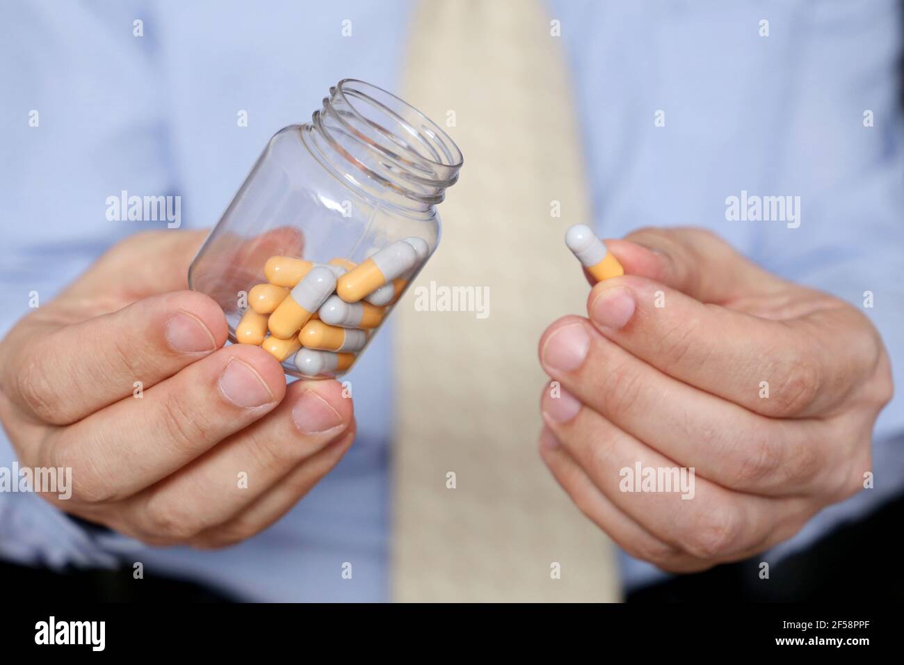 Homme dans les vêtements de bureau prenant des pilules, bouteille de médicament dans les capsules de près. Concept d'antidépresseur, stress au travail, vitamines, dose de médicaments Banque D'Images