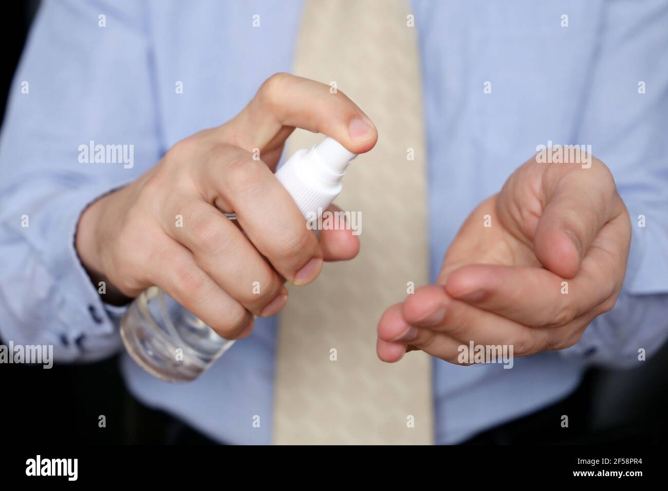 Homme dans des vêtements de bureau désinfectant ses bras la peau, la prévention de l'infection du coronavirus. Mains et flacon de sexe masculin avec vaporisateur d'assainisseur Banque D'Images