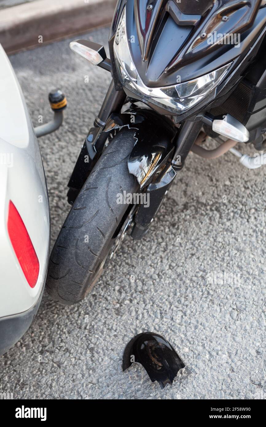 Blessures causées par une collision entre une moto et une voiture, vue rapprochée d'un accident de la route avec des pièces cassées d'une aile en plastique Banque D'Images