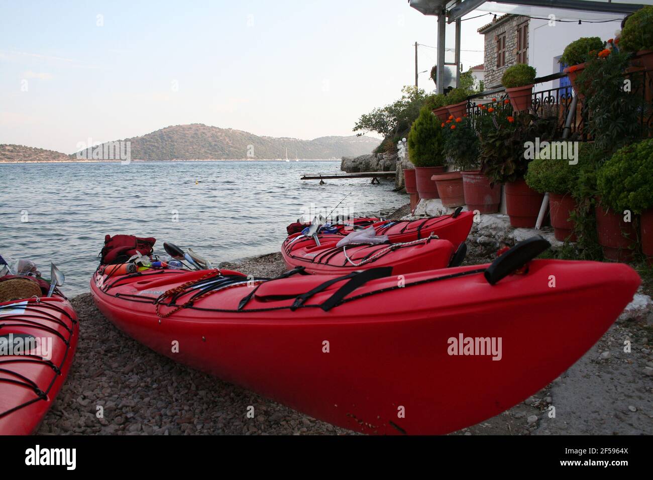 Kayaks de mer sur le rivage, fleurs en arrière-plan et taverne, îles lointaines Banque D'Images