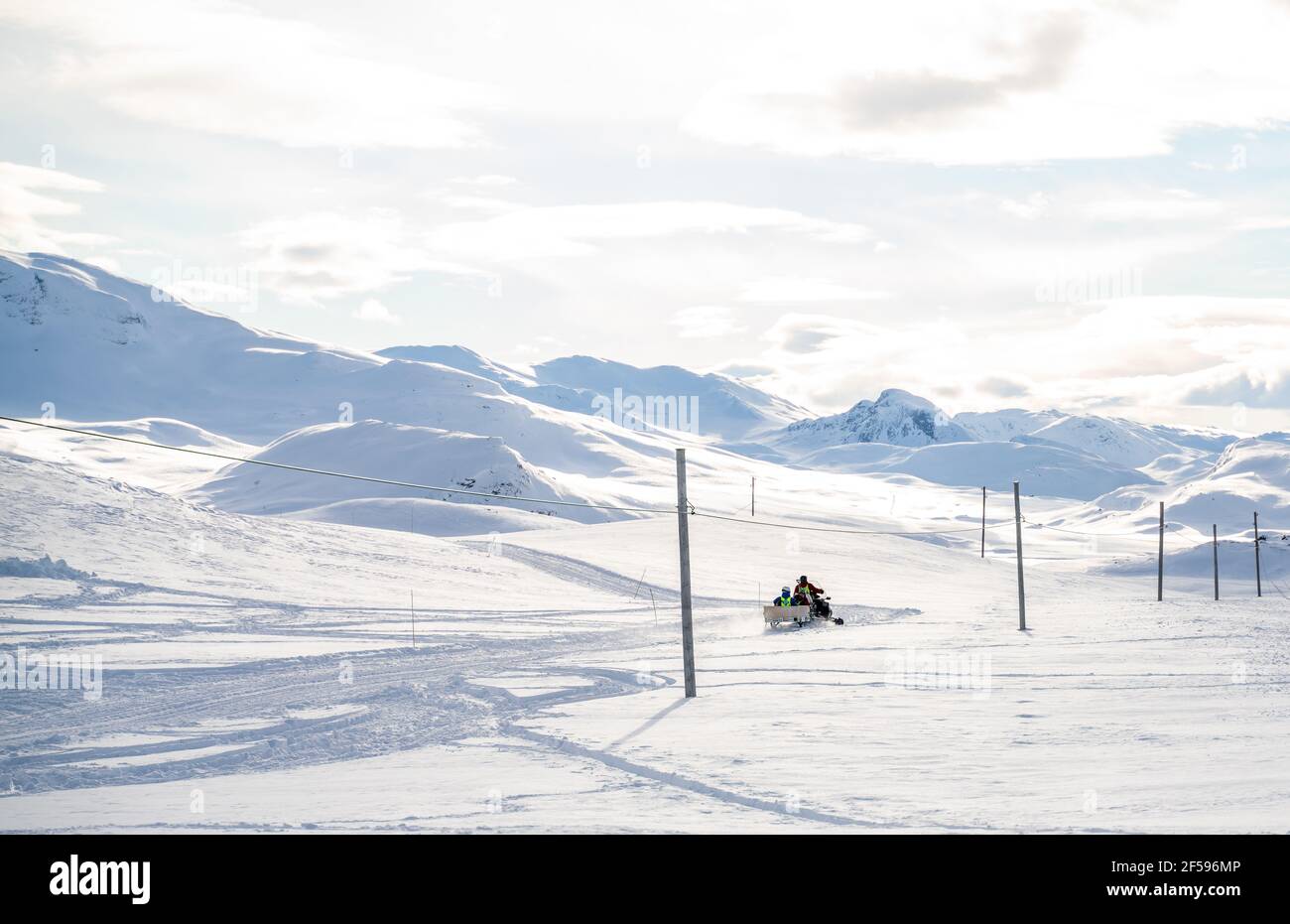 Travailleurs de secours en montagne qui conduisent une motoneige dans les montagnes d'hiver. Banque D'Images