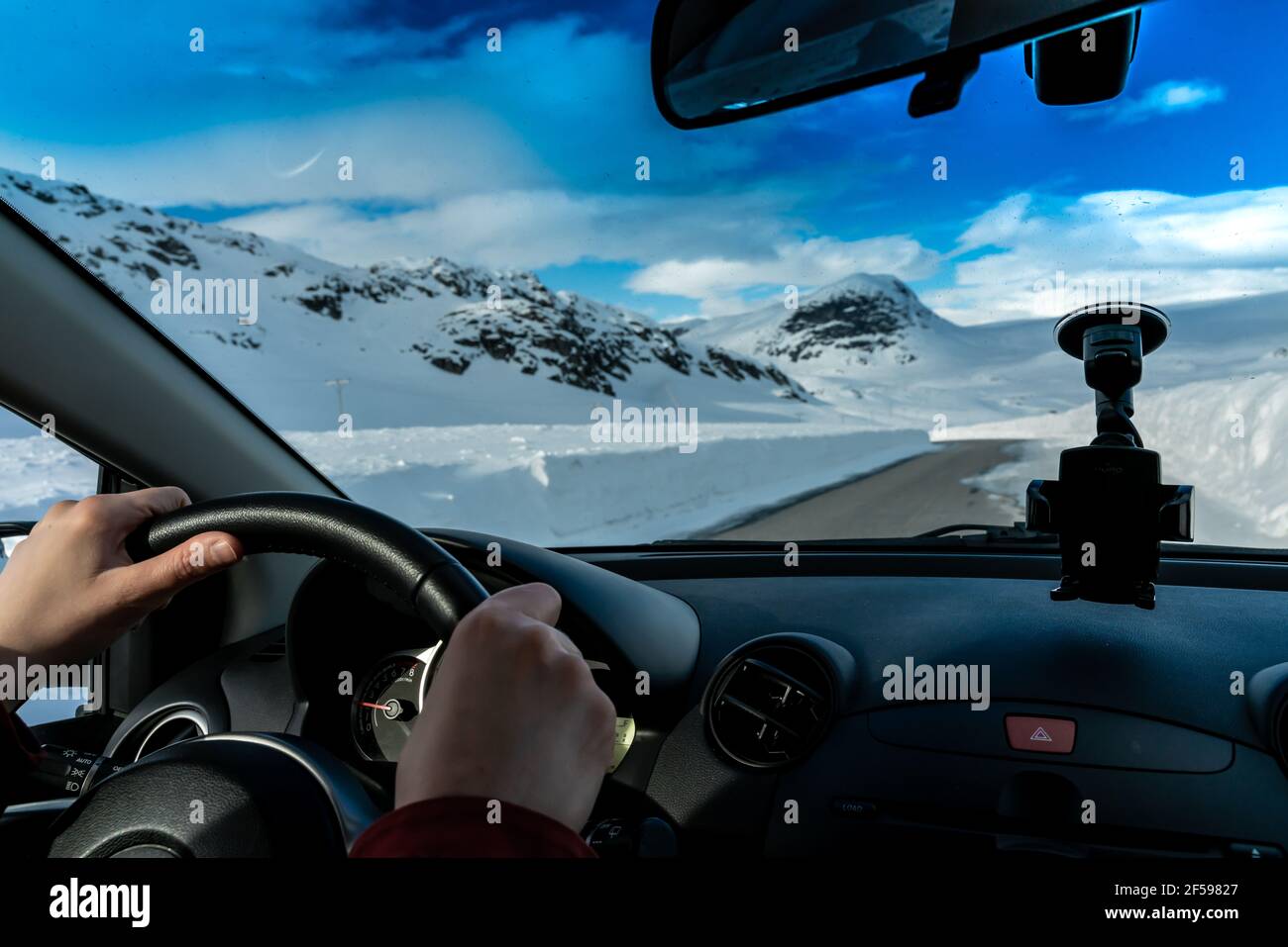 Mains sur le volant d'une voiture roulant en col de montagne. Banque D'Images