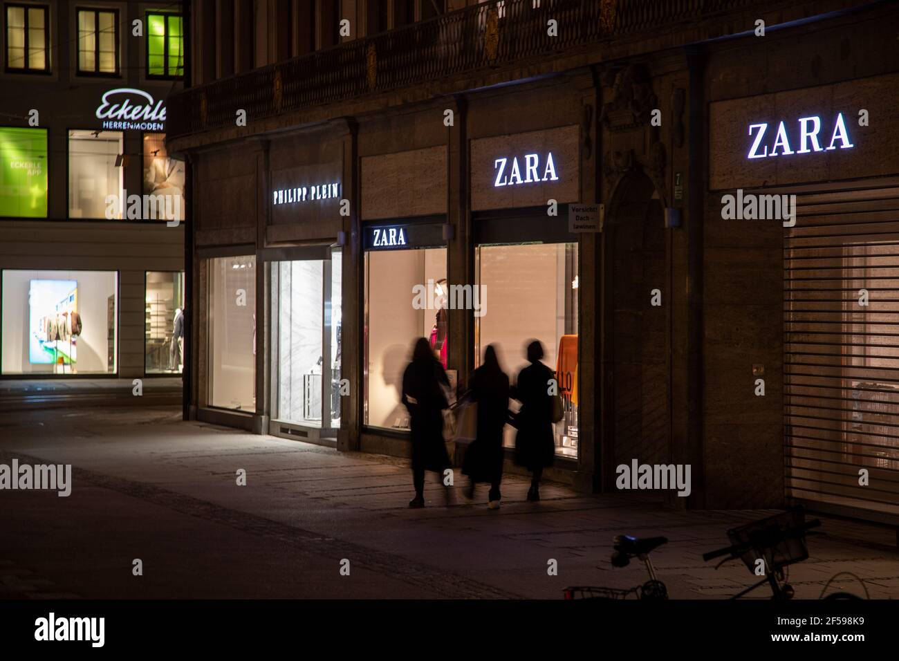 Shopper mit Einkaufstüten gehen am Zara und Philipp plein vorbei. Die Münchner Innenstadt und Fußgängerzone ist am Abend/Nacht des 24.3.2021 ziemlich leer. - la zone piétonne de Munich est presque vide dans la nuit du 24 2021 mars. (Photo par Alexander Pohl/Sipa USA) crédit: SIPA USA/Alay Live News Banque D'Images