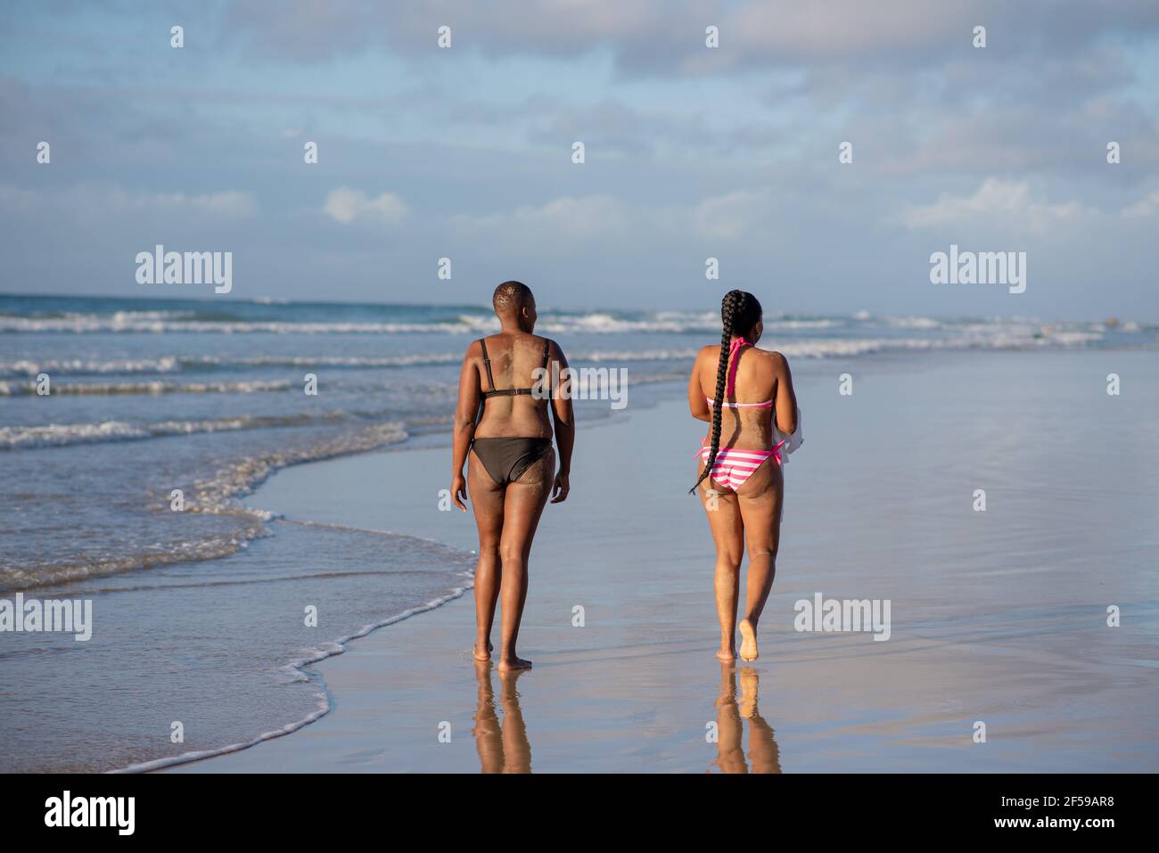 Femme marchant le long de la plage avec des vagues vues en arrière-plan Banque D'Images