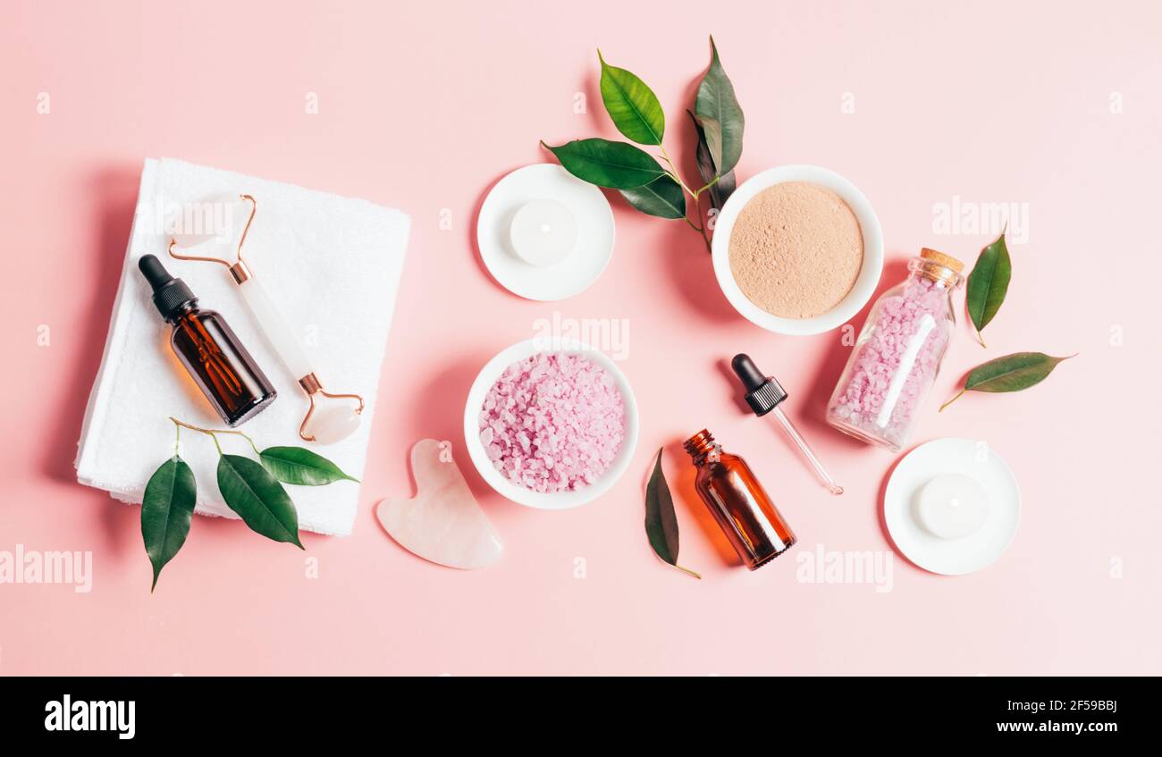 Composition spa sur fond rose pastel. Cosmétiques naturels bio bouteille d'huile, crème, argile, sel, outil de massage gua sha accessoires plan Banque D'Images