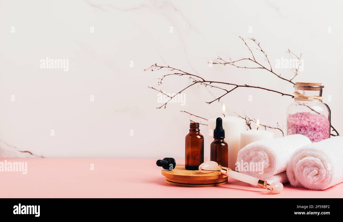 Composition spa sur fond rose pastel. Cosmétiques naturels bio bouteille d'huile, crème, argile, sel, outil de massage gua sha accessoires plan Banque D'Images