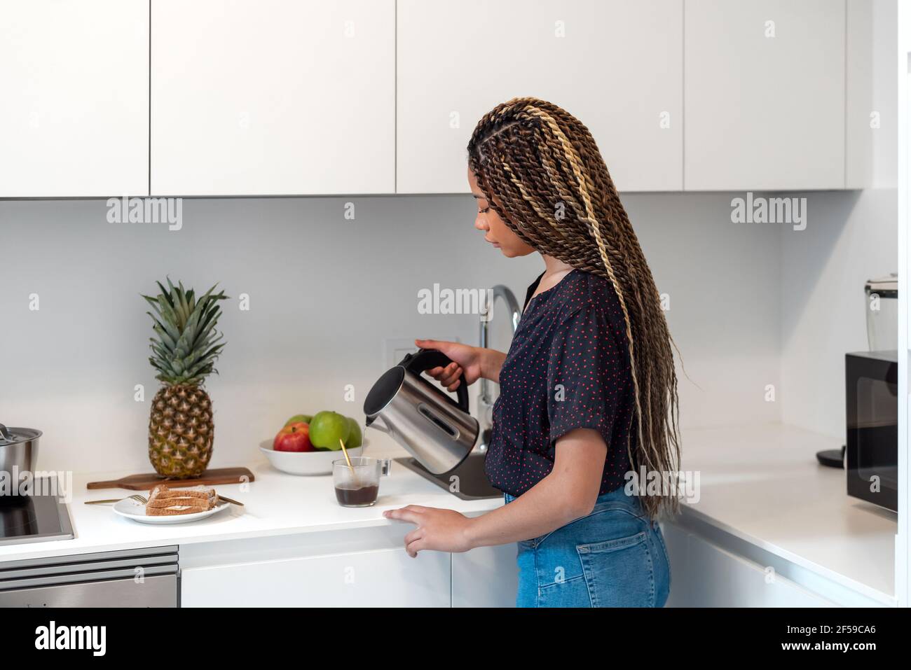 Femme préparant du café soluble à la maison tout en préparant un petit déjeuner sain dans la cuisine Banque D'Images