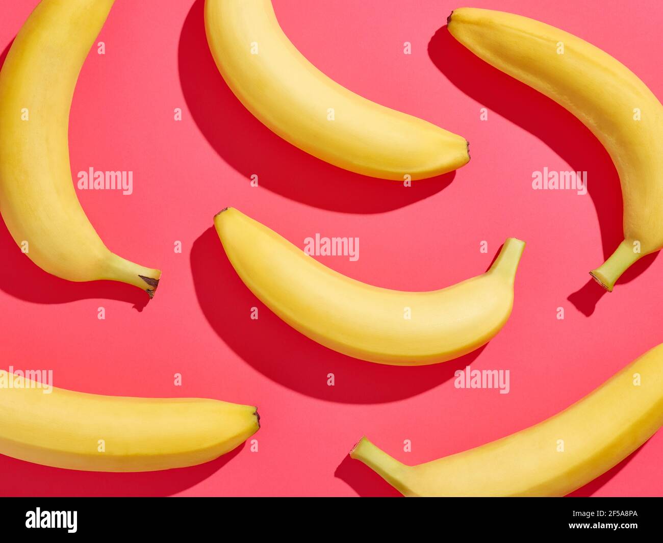 Motif de banane coloré sur fond rose, d'en haut, ombre dure Banque D'Images